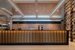 Industrial-style coffee shop interior with brick wall, wooden shelving, and glass coffee makers.