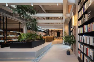 An industrial-style library with concrete floors, wooden shelves, and brick walls.