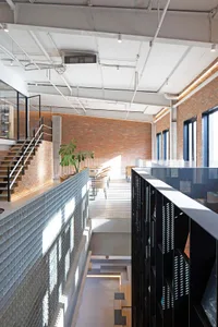An industrial-style office space featuring brick walls, glass elements, and concrete finishes.