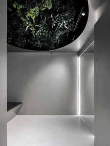Industrial-style interior with vertical greenery, featuring a variety of artificial plants mounted on a concrete wall.