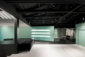 Interior shot of a minimalist retail space featuring a concrete floor and wall-mounted light fixtures.