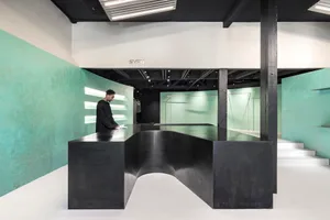 A modern retail storefront with a sleek black curved reception desk, turquoise walls, and white flooring.