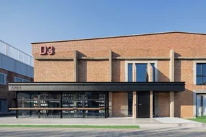 Modern industrial retail storefront with brick and concrete materials, featuring a black overhang.