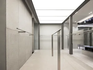 A minimalist clothing retail store featuring concrete, metal, and glass elements.