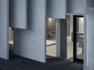 Modern minimalist interior featuring marble walls and floors, with a central seating area in the background.