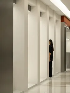 A modern office hallway with tall, white concrete columns and a polished tiled floor.