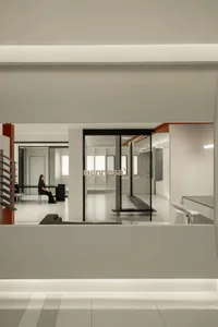 A modern office space with transparent glass walls and floor-to-ceiling windows.