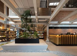 An industrial-style coffee shop/library with brick walls, concrete flooring, and metallic accents.