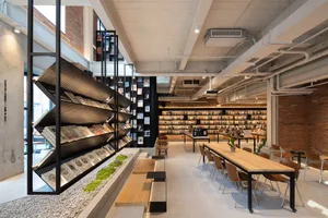 Industrial-style library with concrete walls, metal shelves, and wooden tables.