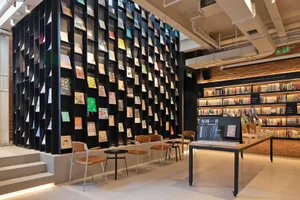 Modern bookstore with metal shelves displaying books and seating areas.