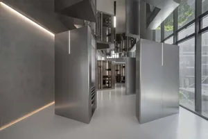 Modern industrial commercial kitchen with stainless steel appliances and concrete flooring.