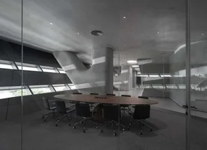 A minimalist conference room with concrete walls and a large oval table surrounded by black chairs.