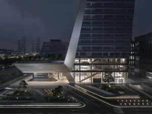 Nighttime exterior view of a modern office building with glass facade and concrete plaza.