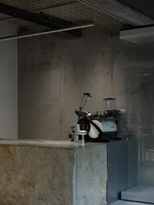 Modern coffee shop interior with a concrete counter and industrial coffee machine.