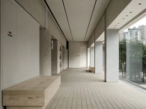 A modern corridor with a white wall and concrete flooring.