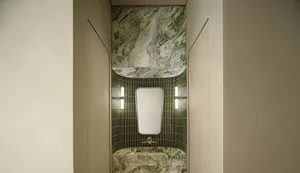A sleek, modern bathroom with green marble tile and a mirror above a sink.