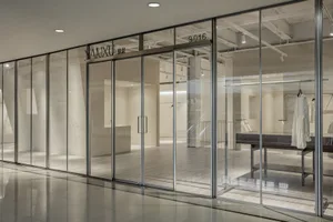 Glass wall of a clothing store displaying garments.