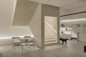 Modern minimalist interior with concrete elements, featuring a geometric staircase and a minimalistic seating area with chair