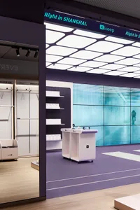 A minimalist retail storefront featuring white painted walls and large glass windows.