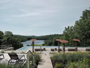 Concrete flooring in a modern residential house with a pool and view of a serene lake surrounded by nature.