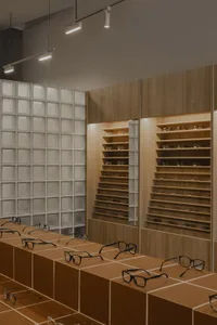 現代眼鏡陳列於木質貨架與玻璃磚牆的光學眼鏡店內。