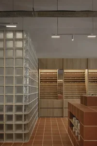 Modern optical store with glass brick walls and wood shelves displaying eyewear.