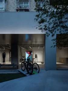 Modern retail storefront with concrete and glass materials, featuring a bicycle in the foreground and a digital screen displa