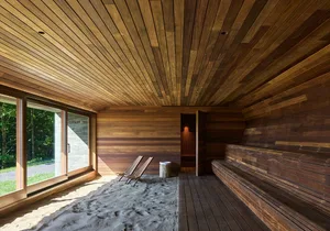 Modern wooden sauna with sand flooring and seating.