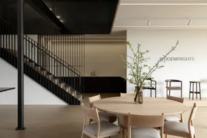 Modern interior design featuring a wooden table with a vase of plants and a staircase in the background.