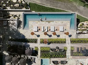 A modern outdoor space with stone pool, lounge chairs, and landscaping