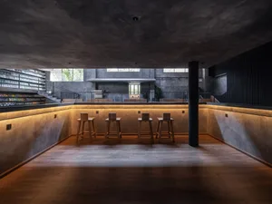A modern bar area with concrete seating and warm lighting.
