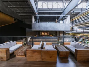 A modern industrial library restaurant featuring exposed concrete ceilings, wooden furniture, and a spacious, open design.