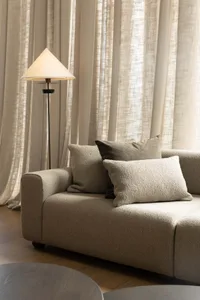 A modern living room featuring textured fabric curtains and a comfortable sofa with soft cushions.