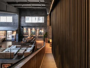 Interior of an industrial-style office space with concrete walls and floors, featuring modern furniture and art displays.