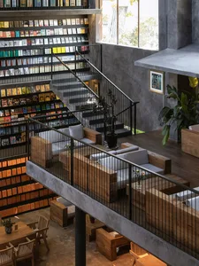 A modern industrial library and child's playroom with concrete and wood materials, featuring seating and bookshelves.