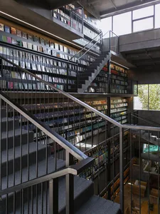 An image of a modern library with concrete bookshelves and stairs.