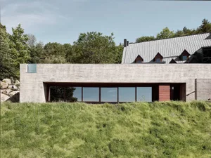 Modern residential exterior with concrete facade and large glass windows.
