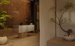 A minimalistic lobby with concrete finishes, plants, and a reception desk.