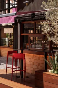 An industrial-style cafe interior with wood accents, high stools, and potted plants.