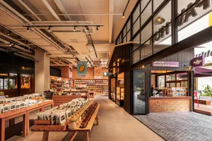 Industrial-style retail space featuring brick walls, wooden tables, metal shelving units, and glass windows.