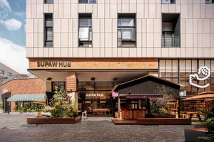 Modern industrial storefront with brick and concrete accents, featuring a welcoming entrance area and a wooden awning.