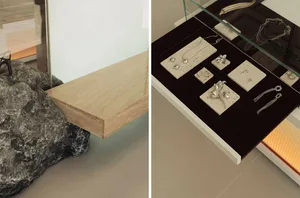 A modern jewelry display featuring a concrete slab with various pieces of jewelry placed on stone slabs.