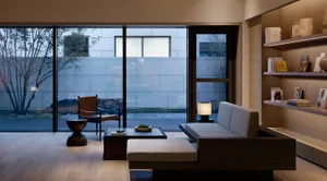 A minimalist living room featuring a wooden floor, couch, and side table.