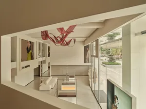 Interior of a modern architecture glass retail shop with a minimalist design and artistic ceiling sculpture.