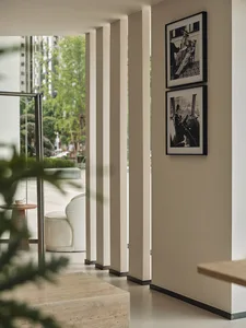 Modern minimalist interior space with white walls, columns, and photographs on the wall.
