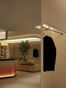 A modern retail storefront with natural elements, featuring a large tree and greenery inside, illuminated by soft, ambient li