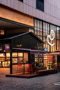 Outdoor seating area with red stools, brick-cladding storefront, and large glass window.