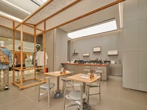 A minimalist cafe interior featuring a concrete base, clean lines, and a functional layout with seating and a counter.