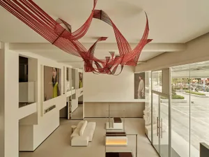 Modern showroom lobby featuring minimalist decor with red textile art hanging from the ceiling.