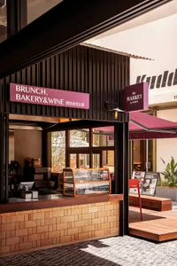 A modern entrance to a brunch bakery, featuring a brick and metal facade with a glass door and awning.